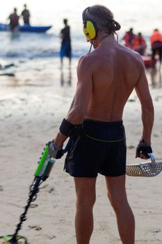 a treasure hunter with Metal detector on the beach