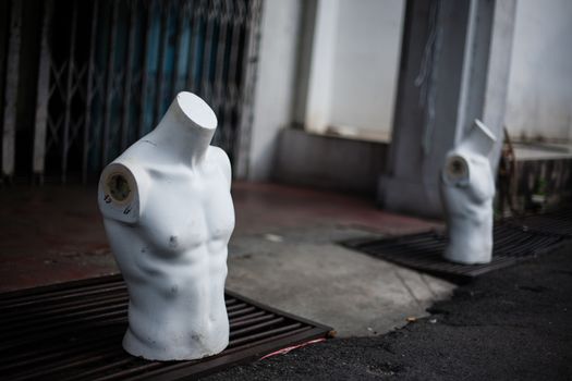 Torso male mannequin stand on the street near gutters