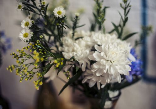 A simple bouquet of flowers in a vase on the pavement close up