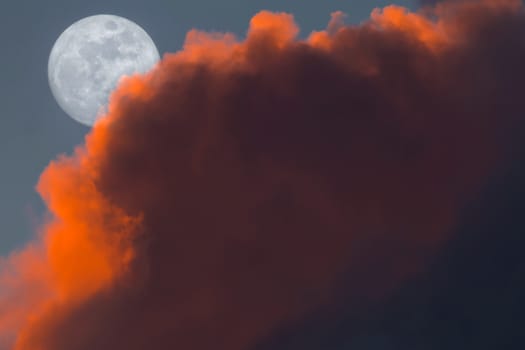 Full Snow Moon Rise peeking behind pink clouds during sunset