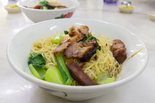 Char Siew Barbecue Pork Wanton Noodles with green vegetable dried on table version closeup macro