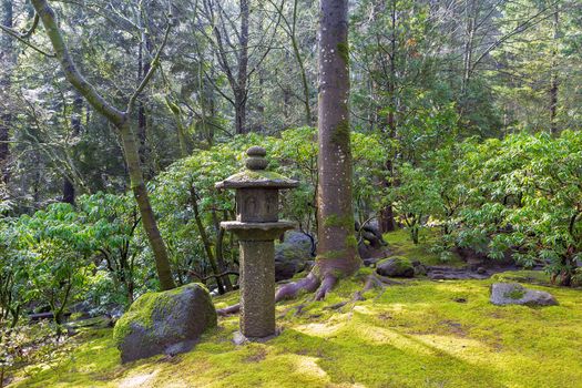 Stone Pagoda Lantern Sculpture at Japanese Garden with trees shrubs rocks moss landscaping