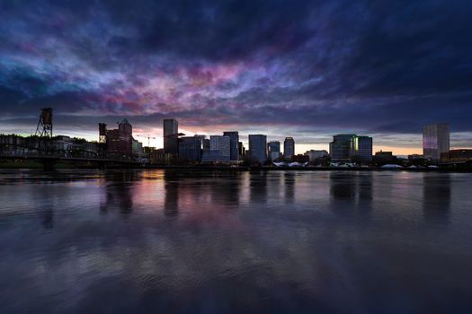 Portland Oregon downtown city skyline from Eastbank Esplanade along Willamette River waterfront during cloudy twilight evening