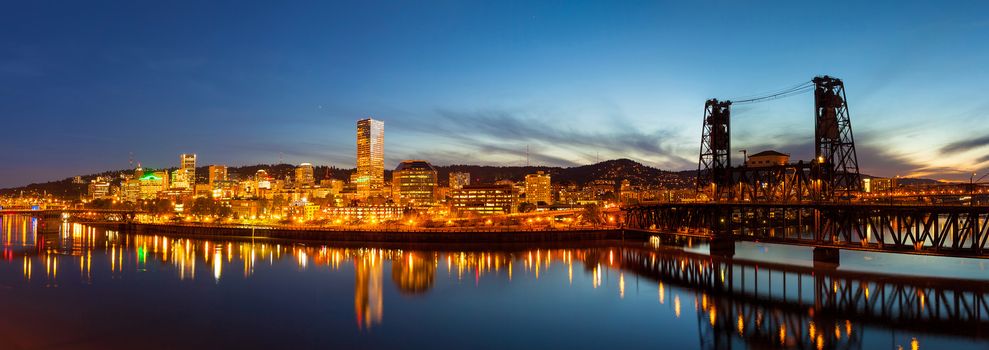 City of downtown Portland Oregon skyline along Willamette River by Steel Bridge during evening blue hour panorama