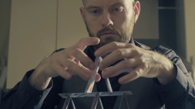 Portrait of a man building a house of a playing cards.