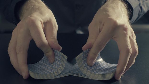 Poker game - shuffling cards. Man's hands shuffing cards. Close up