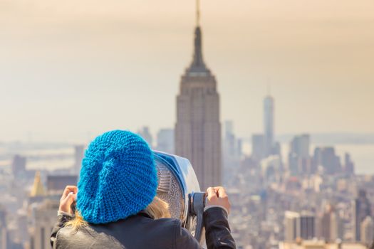 Woman enjoying in New York City panoramic view. Manhattan downtown skyline with illuminated Empire State Building and skyscrapers seen from observation deck terrace.
