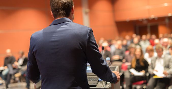 Speaker giving a talk on corporate Business Conference. Audience at the conference hall. Business and Entrepreneurship event.
