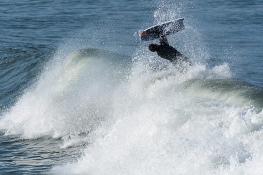 Bodyboarder in action on the ocean waves on a sunny day.