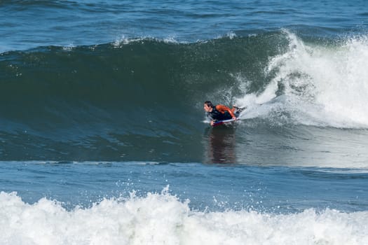 Bodyboarder in action on the ocean waves on a sunny day.