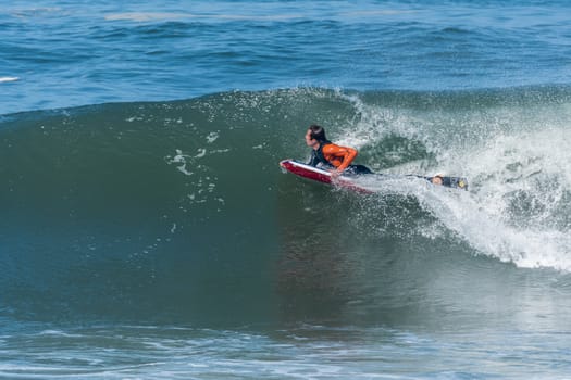 Bodyboarder in action on the ocean waves on a sunny day.