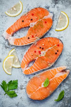 Fresh salmon fillet sliced flat lay on shabby metal background. Raw salmon fillet and ingredients parsley ,sweet basil leaves ,fennel ,pepper corn and lemon for cooking.