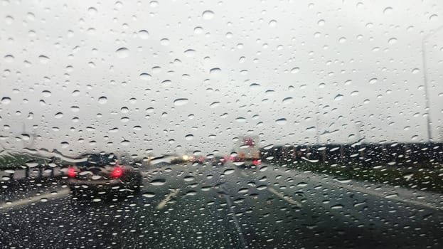 Driving the car on rainy highway. Interior view on wet glass. Point of view shot.