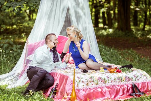 Man and woman sitting on the bed in the lawn and man undressing woman in Lviv, Ukraine.