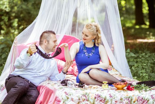 Man and woman sitting on the bed in the lawn and man undressing woman in Lviv, Ukraine.