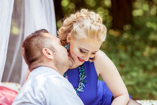 Man and woman sitting on the bed and man kissing woman in the lawn in Lviv, Ukraine.