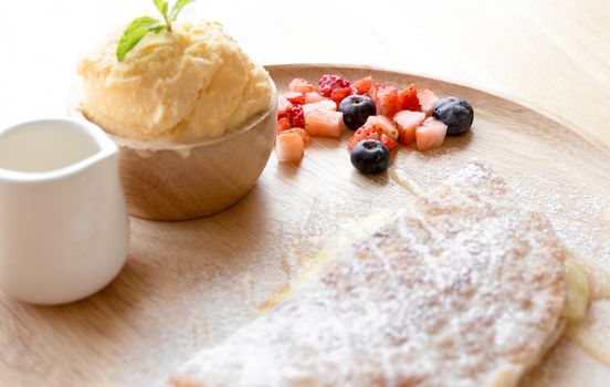 fresh dessert soft vanila roti with ice cream ,syrup ,strawberry and blueberry on plate in restaurant ,selective focus