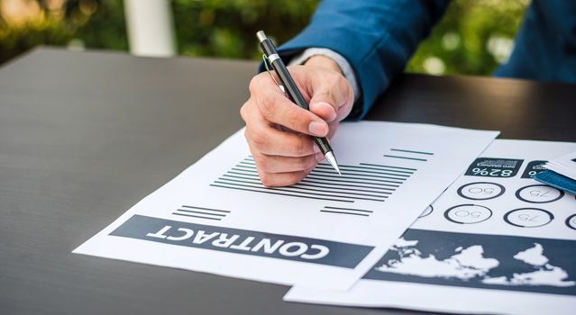 Handsome businessman wearing suit and using modern laptop outdoors and graph finance diagram.