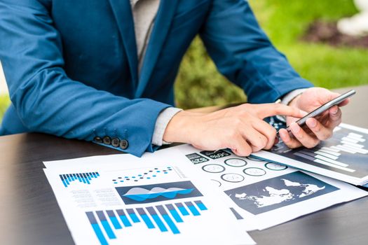 Handsome businessman wearing suit and using modern laptop outdoors and graph finance diagram.