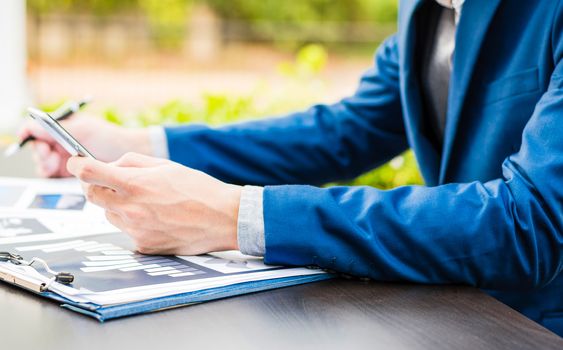 Handsome businessman wearing suit and using modern laptop outdoors and graph finance diagram