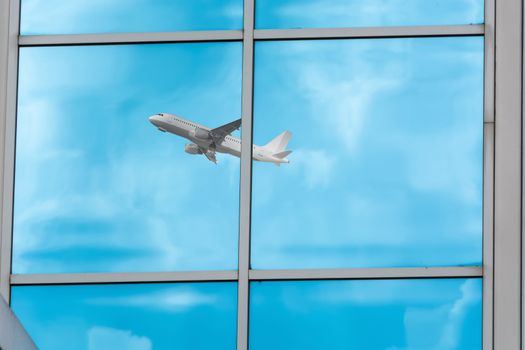 Beautiful glass building facade with reflections of an airplane during startup.