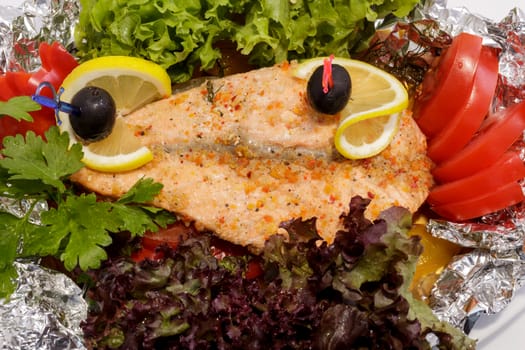 freshly cooked fish and fresh vegetables on the plate. Close-up view from above.