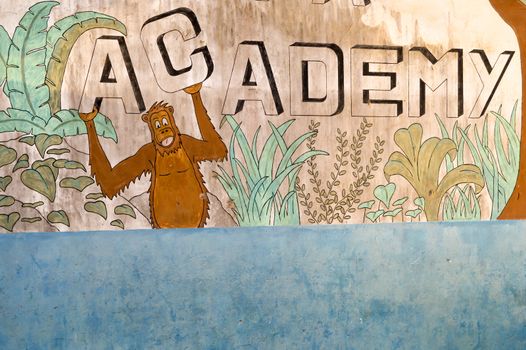 Painting on the wall of a school with the word academy and an Oran outan under the letter C