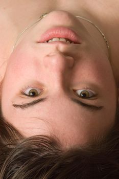 A young woman staring into the camera in an upside-down position
