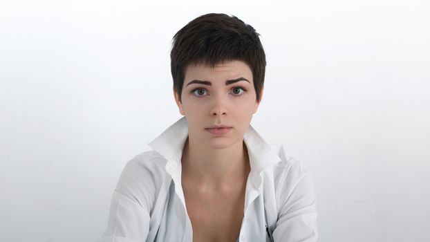 Dramatic portrait of sad businesswoman in white shirt with bobbed hair looking at the viewer.