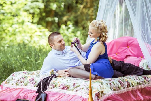 Man and woman sitting on the bed in the lawn and woman undressing man in Lviv, Ukraine.