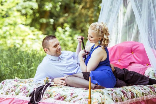 Man and woman sitting on the bed in the lawn and woman undressing man in Lviv, Ukraine.