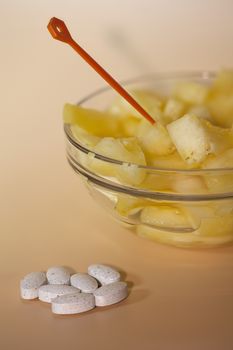 handful of pills and cup filled with pineapple slices concept of healthy nutrition and prevention medicine