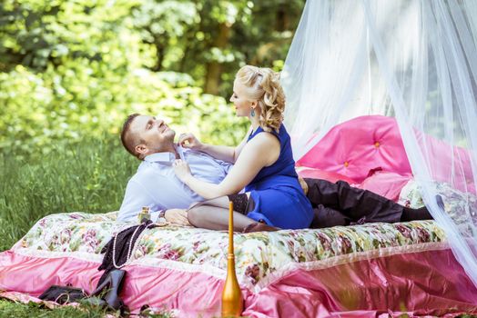 Man and woman sitting on the bed in the lawn and woman undressing man in Lviv, Ukraine.