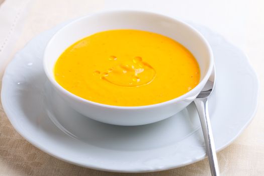 Pumpkin soup with cream served on a table.