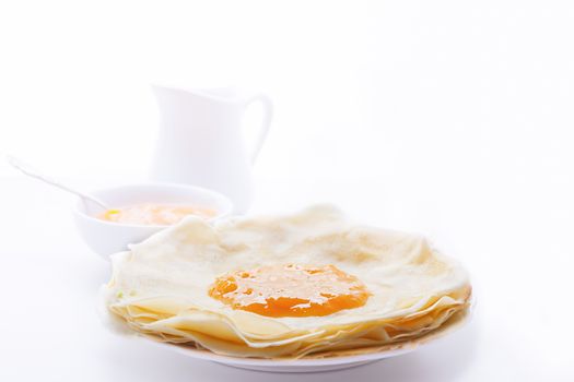 Crispy crepes with apricot jam on a white plate