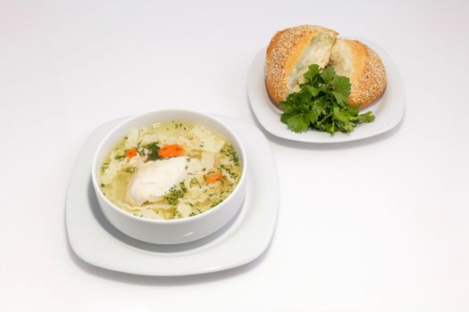 Chicken noodle soup and bun with sesame seeds and herbs