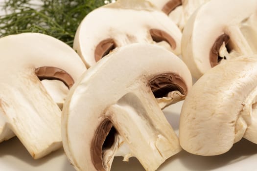 Cut champignons on a plate with greens. Close-up