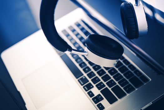 Modern Computer and Elegant Wireless Headphones on the Glassy Desk.