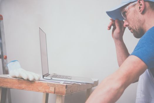 Construction Business Concept. Caucasian Worker with Laptop Computer Checking Project Schedule.