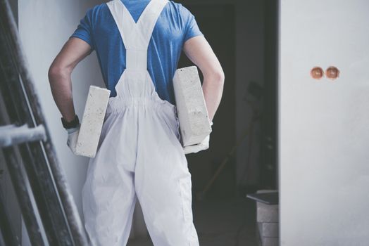 Construction Worker Job. Caucasian Worker Moving Building Materials in His Hands.