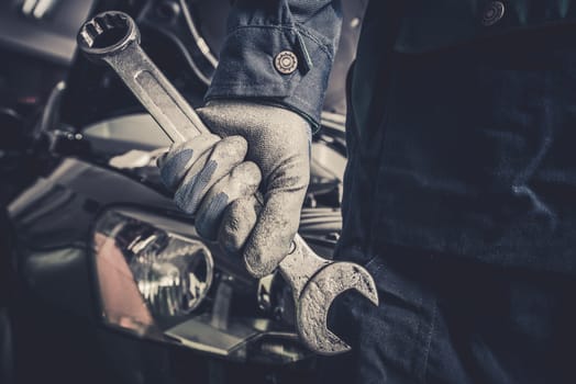 Fixing the Car Concept. Mechanic with Large Wrench is About To Start His Car Maintenance and Fix Work.