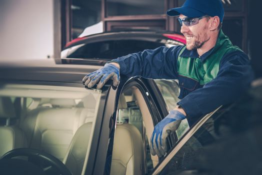 Happy Car Mechanic in His Small Garage Auto Service Shop. Small Business Concept.