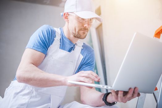 Homes Renovation Business. Caucasian Construction Worker with Laptop Computer.