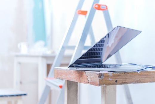 Laptop with Home Remodeling Plans on the Small Wooden Table.