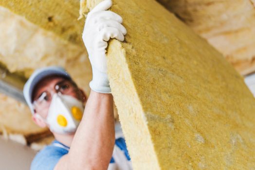 Caucasian Construction Worker with Piece of Insulating Material, Roof Insulating by Mineral Wool.