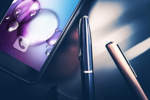 Smartphone in Business. Modern Desk Equipment and Tools. Smartphone and Elegant Pens on the Glassy CEO Desk. Closeup Photo.