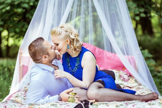 Man and woman sitting on the bed in the lawn and woman undressing man in Lviv, Ukraine.