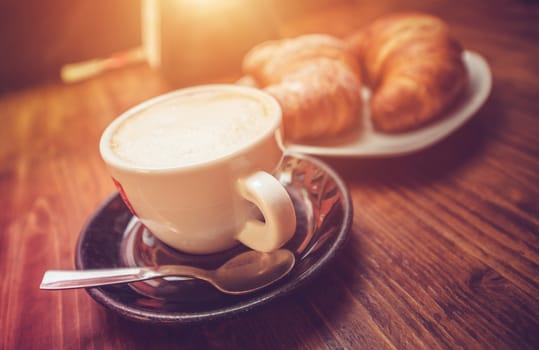 Cappuccino Coffee Time. Freshly Made Cappuccino and Tasteful Croissants on the Wooden Table Somewhere in the Italy.
