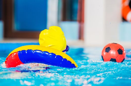Kid Playing the Ball in the Swimming Pool. Closeup Photo. Children Recreation and the Free Time.
