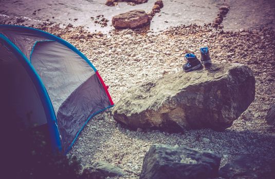 Lake Camping Scenery. Campsite on the Rocky Lake Shore. Outdoor and Recreation Theme. Wet Shoes on the Boulder.